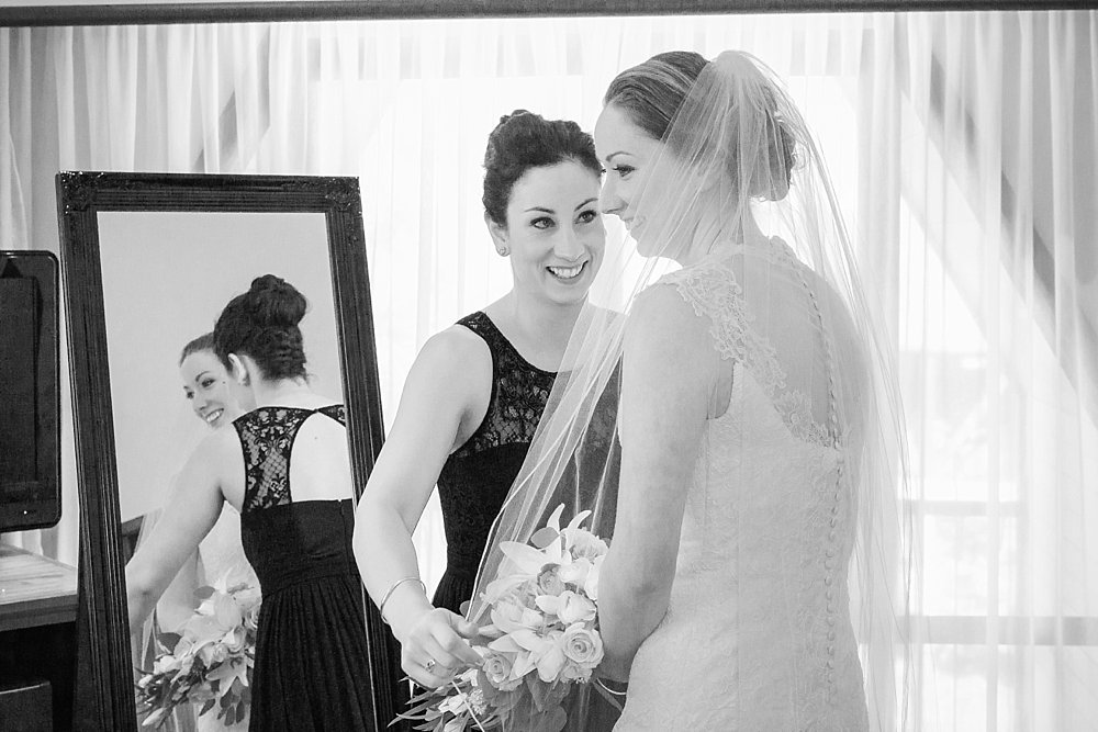 Melton Estate Wedding-Sister and Maid of honour helps the bride put on her veil