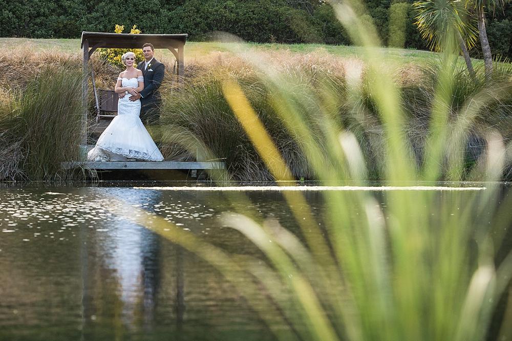 Bride and groom standing across a pond at Flaxton Manor B&B, photo by Wedding Photographers Christchurch Pip and Oz