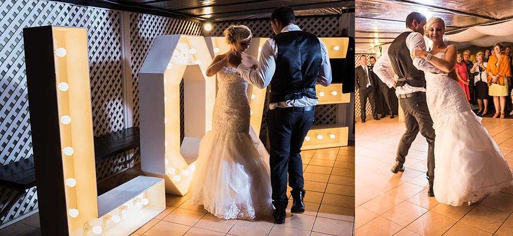 Bride and groom dancing in front of an illuminated Love sign at Bramble Grove Wedding Venue