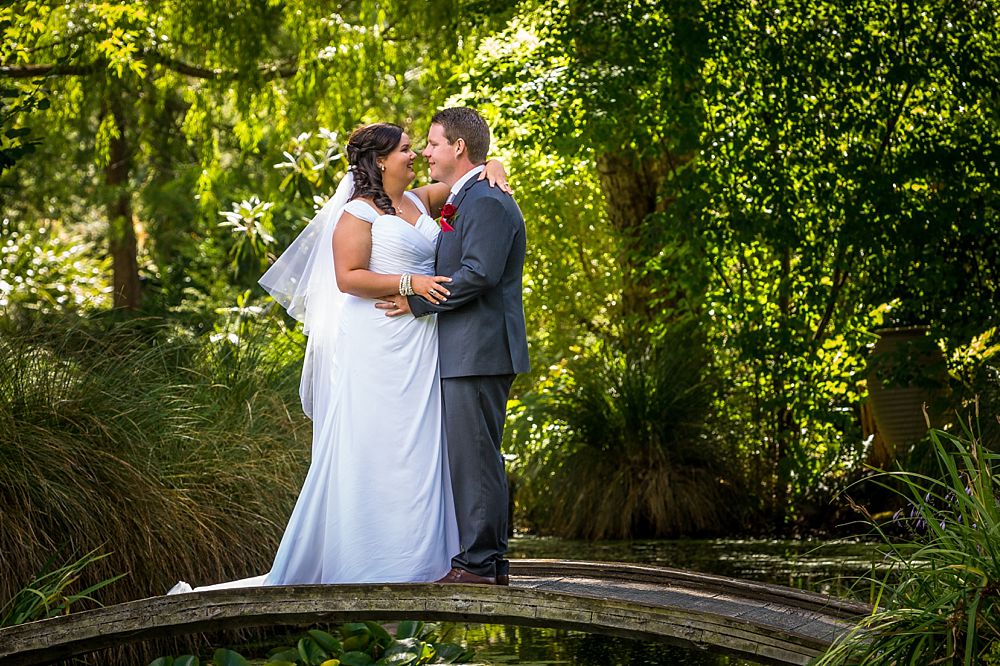 Bride and groom on a pond bridge at Flaxmere Garden Wedding Venue