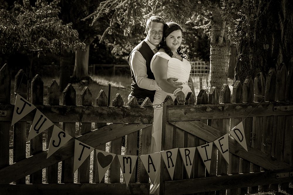 bride and groom by a farm gate at Flaxmere Garden Wedding Venue in North Canterbury