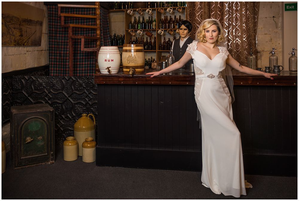 Bride standing with arms on the bar in white wedding dress